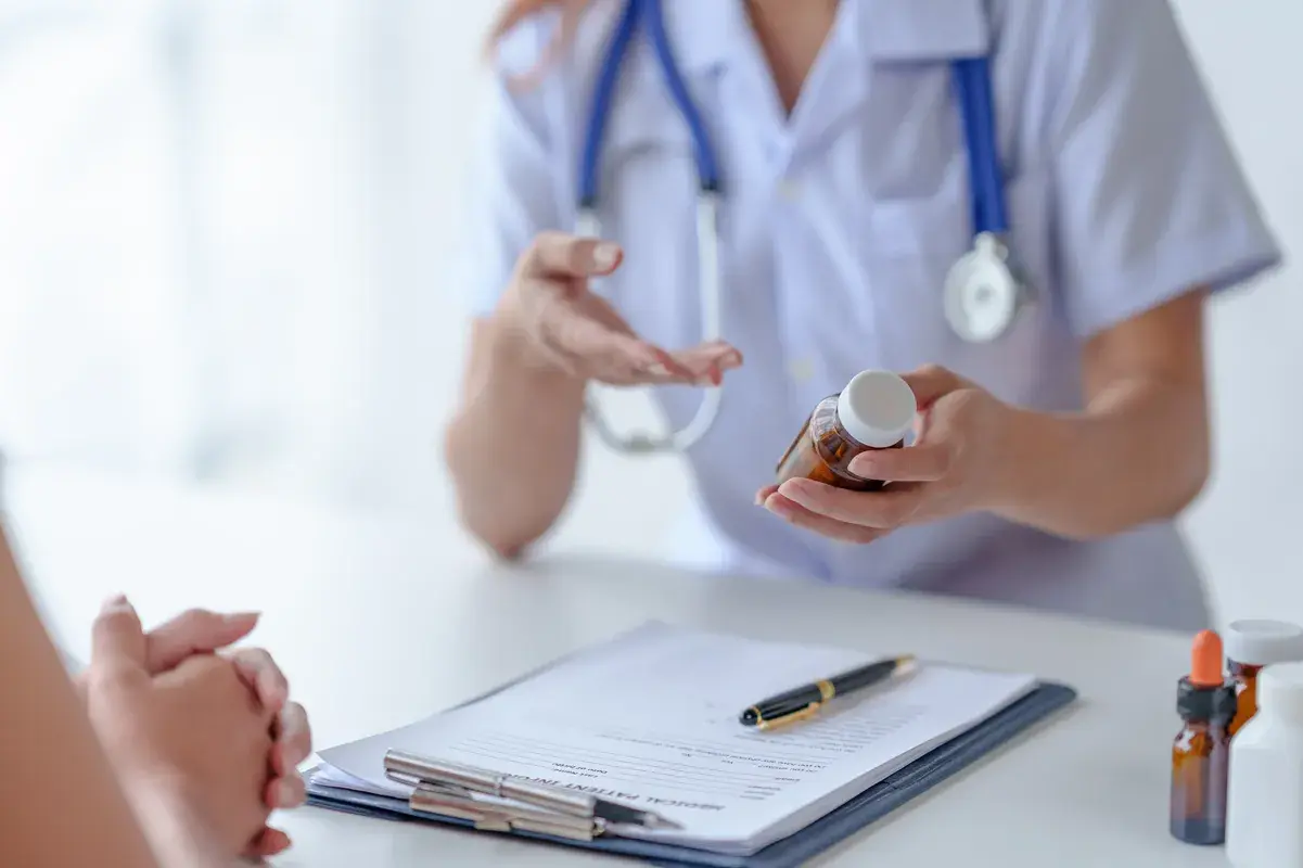 Doctor explaining medication bottle to patient over paperwork