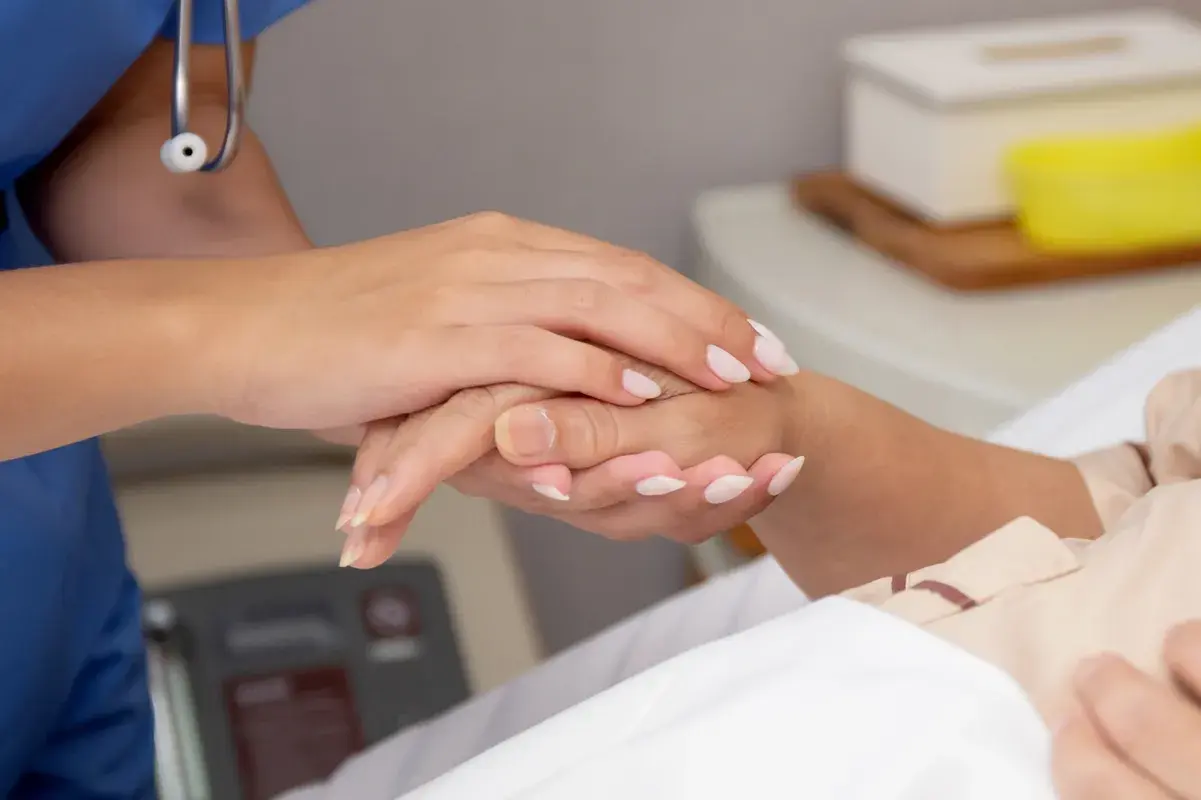 Nurse holding patient's hand offering supportive bedside care